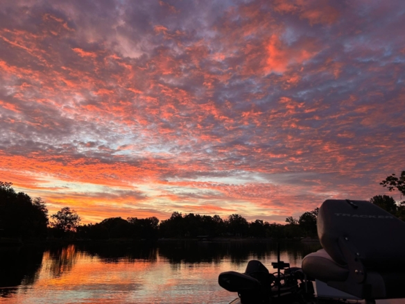 Early Sunrise over Lake of Egypt in Southern Illinois with vibrant pink and orange clouds reflecting on calm water and dockside boat in foreground