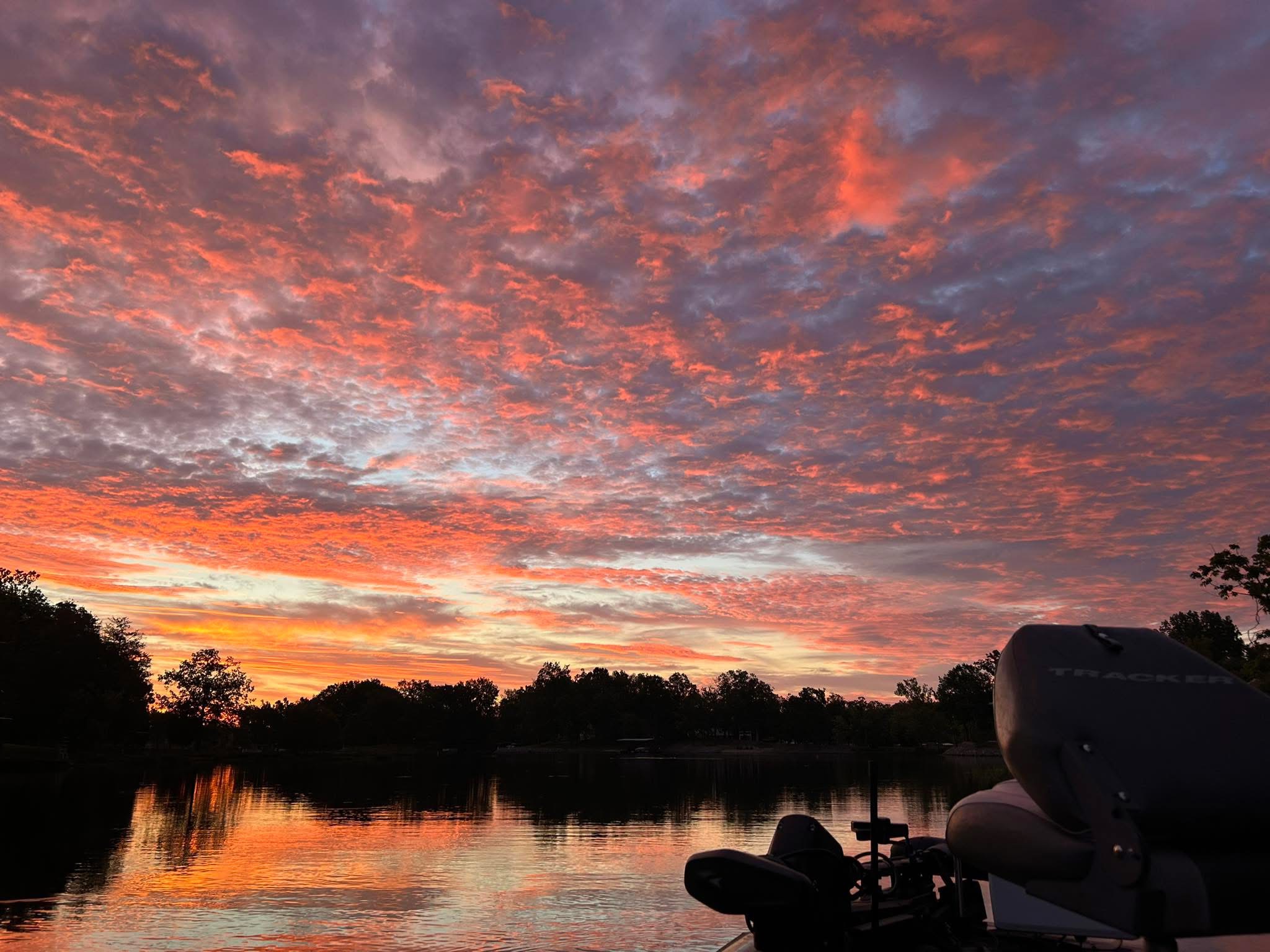Early Sunrise over Lake of Egypt in Southern Illinois with vibrant pink and orange clouds reflecting on calm water and dockside boat in foreground